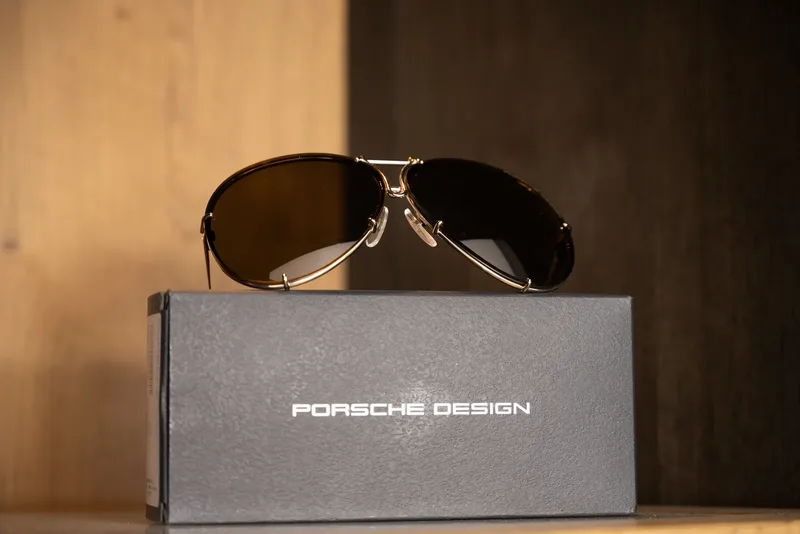 Gold Porsche Design aviator sunglasses resting on their branded case