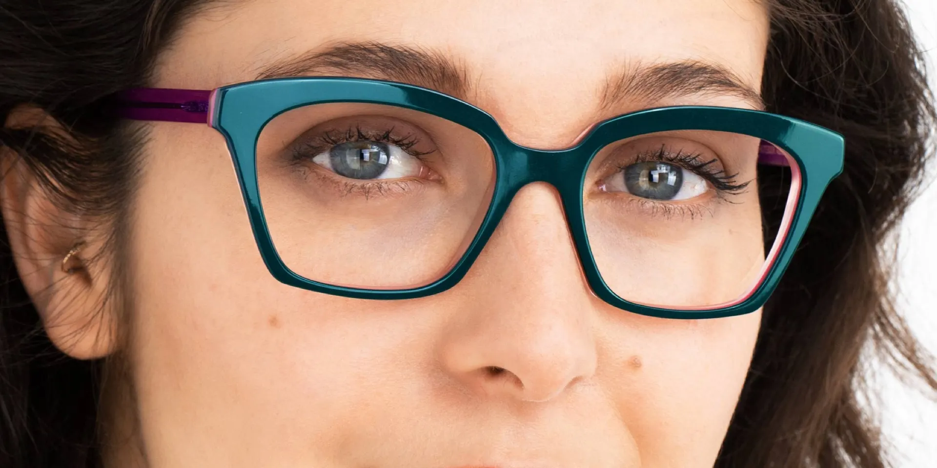 Teal cat-eye frames on a woman with striking blue eyes