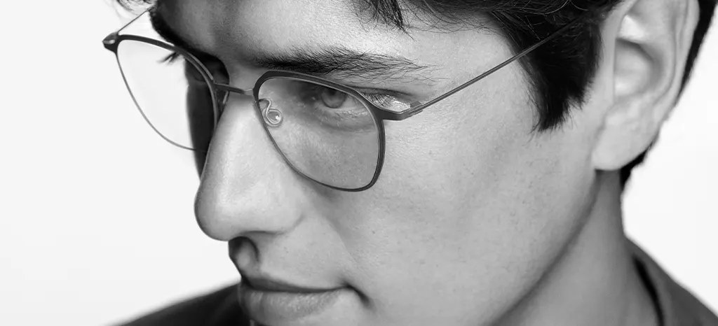 Black-and-white closeup of a man wearing slim Lindberg titanium eyeglasses