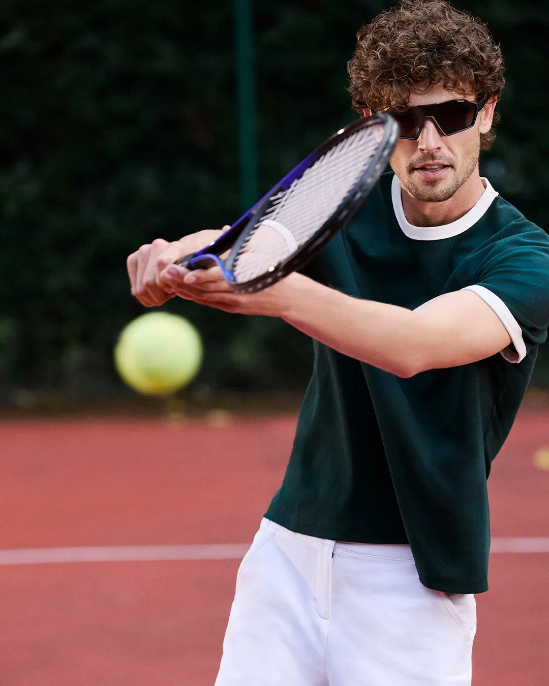 Tennis player mid-swing wearing Polaroid shield sunglasses