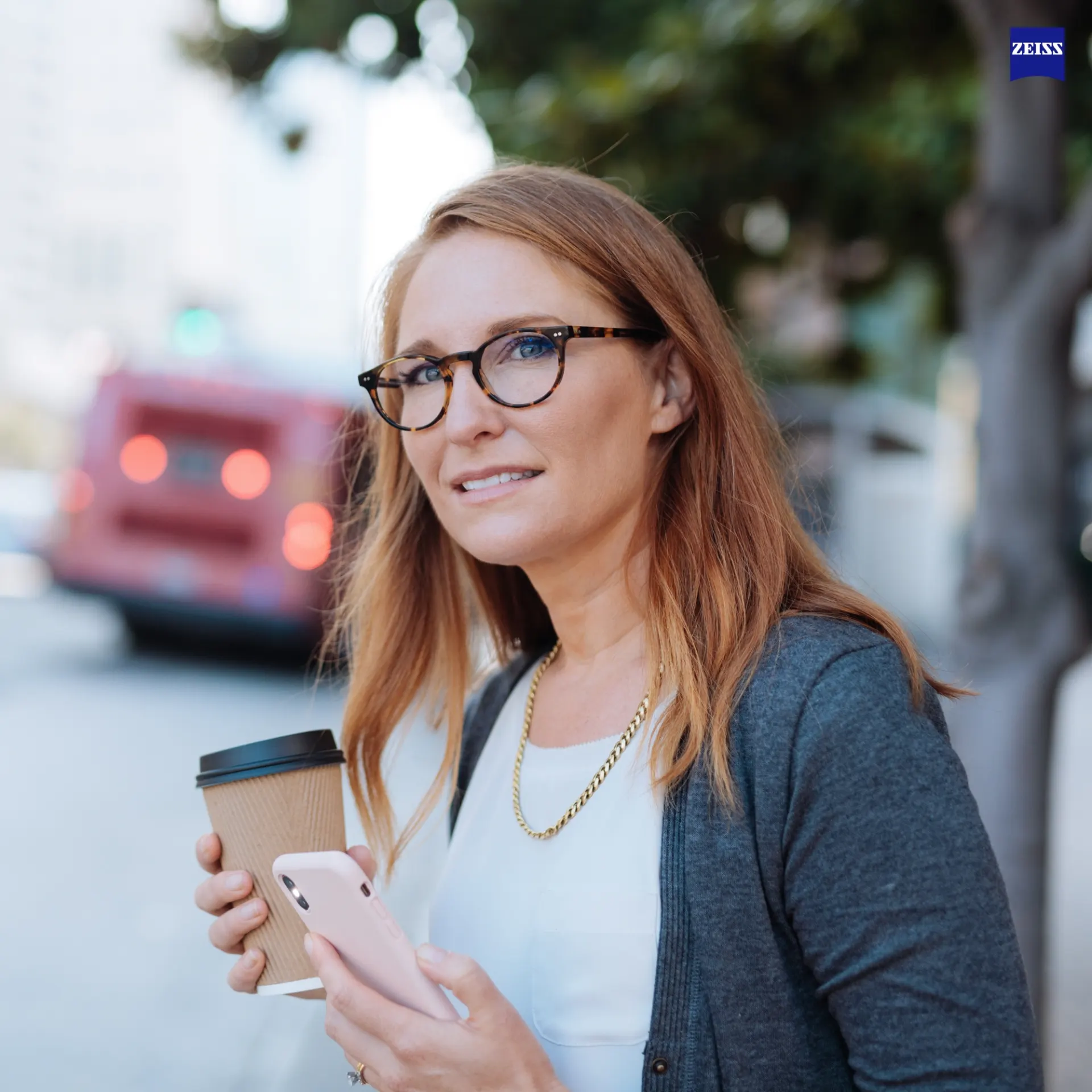 Woman in round tortoise frames with Zeiss SmartLife lenses on a city street